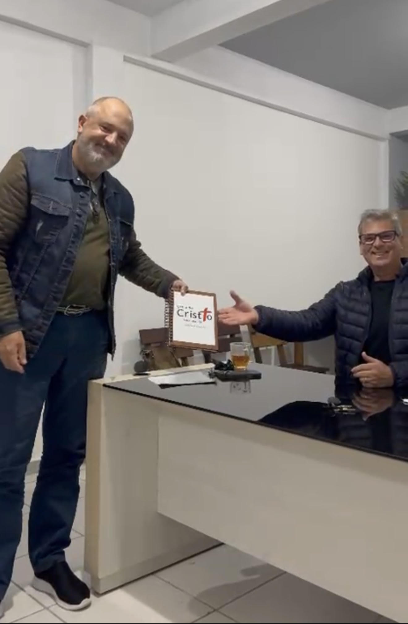 Irmão entregando um caderno de pedidos de oração para outro irmão da igreja.